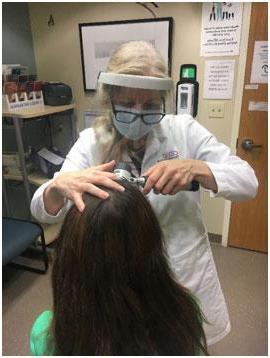 Dr. 使用三角镜检查病人的头皮